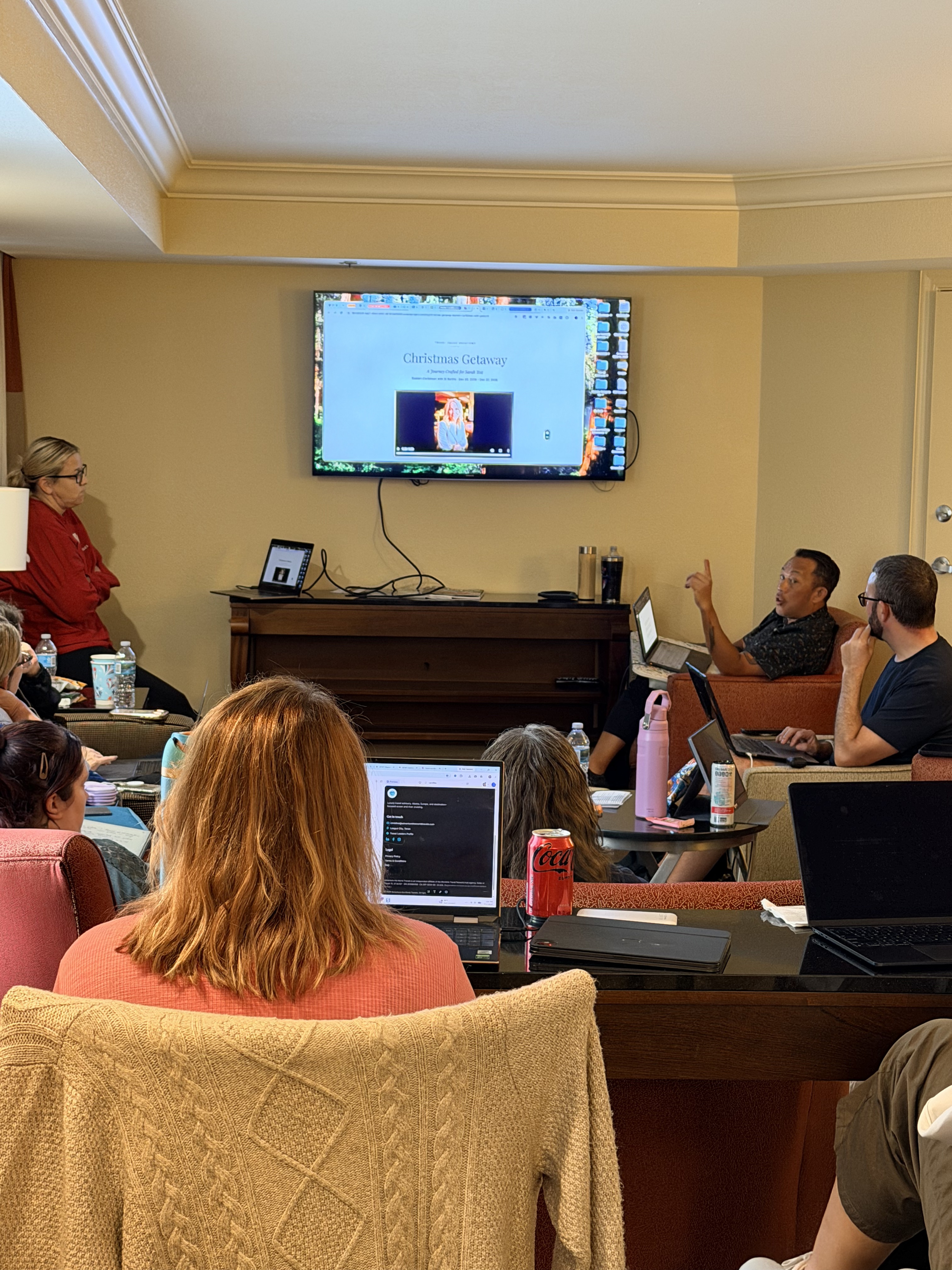 Nicci Grotefendt presenting a travel workshop on screen to MasterClass attendees working on laptops in a Rosen Centre Hotel suite, Orlando